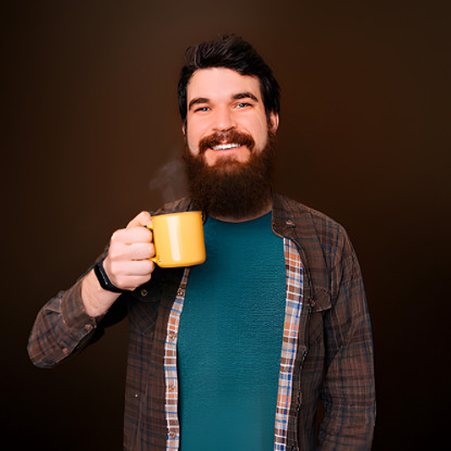 Homem sorridente com barba bebe uma xícara amarela de café Café Pelé
